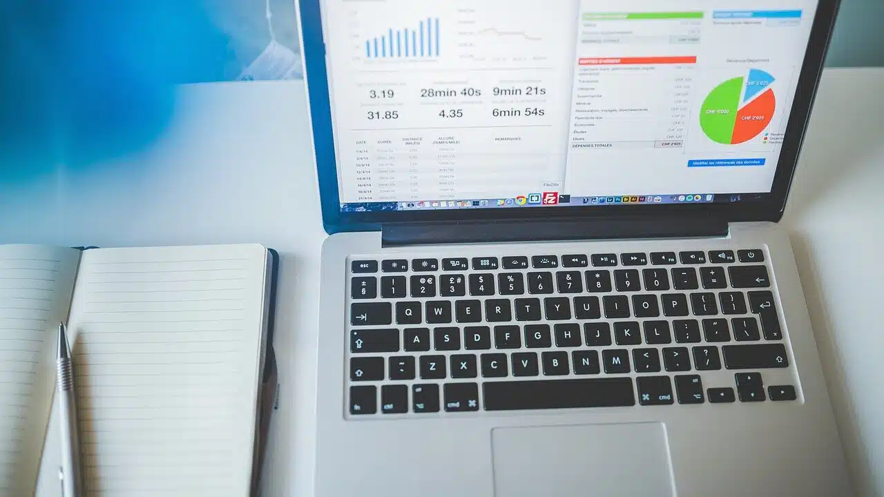 A laptop screen showing business charts next to a notebook on a desk, representing a fleet operator tracking emissions data over time