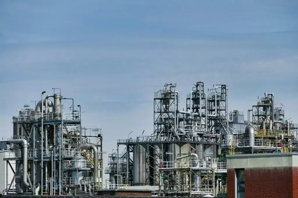 Industrial refinery with pipework, storage tanks, and processing towers, representing the hydrotreatment infrastructure used to refine feedstocks into paraffinic renewable diesel